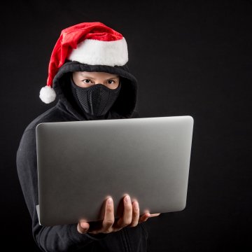 burglar holding laptop christmas hat